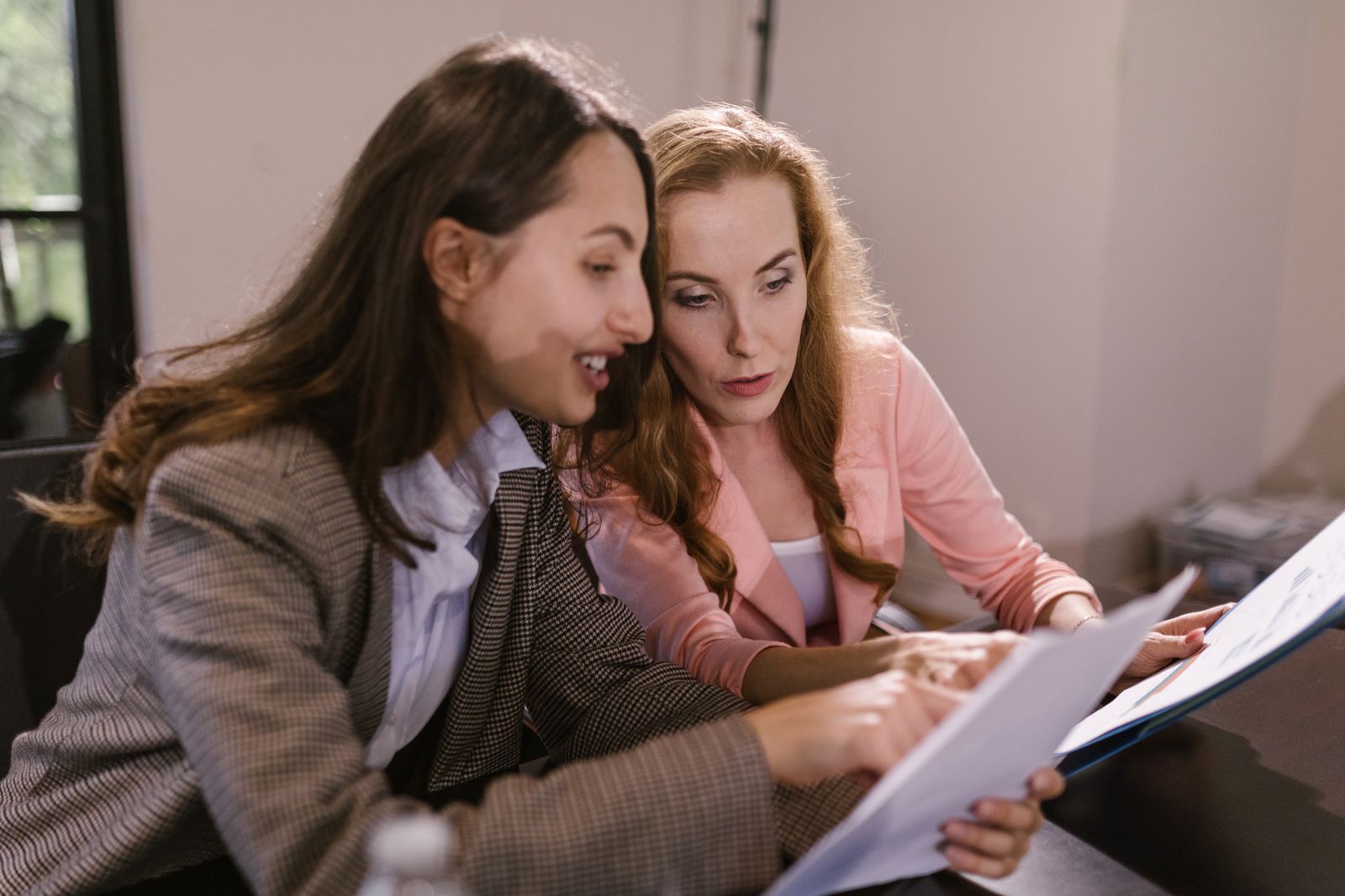 Two colleagues reading a printed document together at a desk